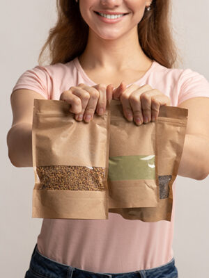 Eco-Friendly Package. Woman holding brown kraft paper doypack bags with weight groceries